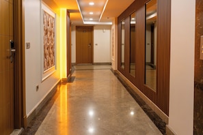 A hotel corridor with wooden doors, a marble floor, and a framed artwork on the wall. - Eliza Hotel (Istanbul)