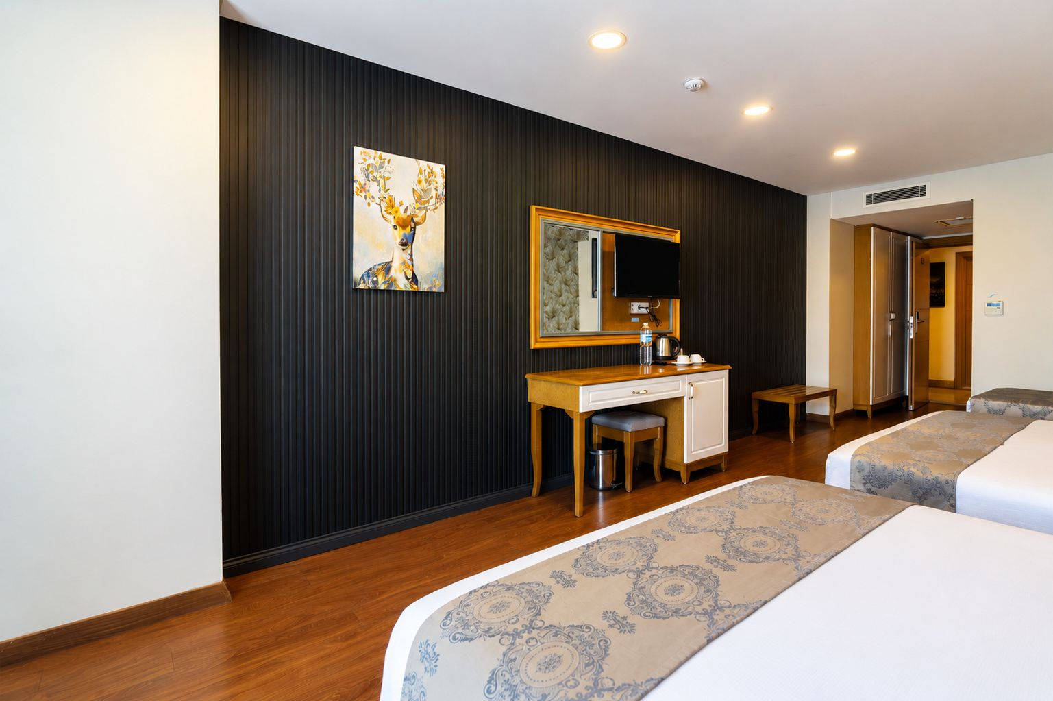 A hotel room with a bed, a desk, a chair, a television, and a painting on the wall.