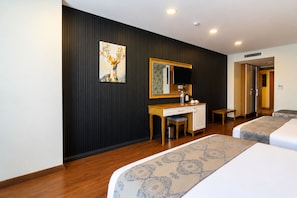 Una habitación de hotel con cama, escritorio, silla, televisor y un cuadro en la pared.