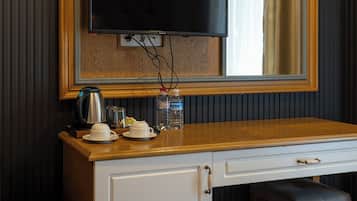 A room with a wooden desk, a television mounted on the wall, a cabinet, and a bench.