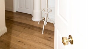 A hallway with a white door, a coat rack, and a small table. - Modern 2 bed flat in historic building (London)