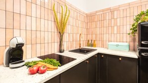 A kitchen with a modern design, featuring a black countertop, a sink, and a coffee machine. - Das Hostel (Kraków)