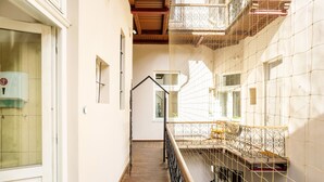 A narrow staircase with a wooden handrail and metal balustrade, leading to a balcony with a metal railing. - Das Hostel (Kraków)