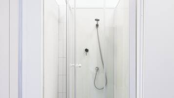 Un box de ducha moderno con puerta de vidrio, cabezal de ducha de mano y asiento integrado.