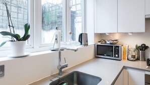 Una cucina moderna con lavello in acciaio inox, forno a microonde e pensili bianchi.