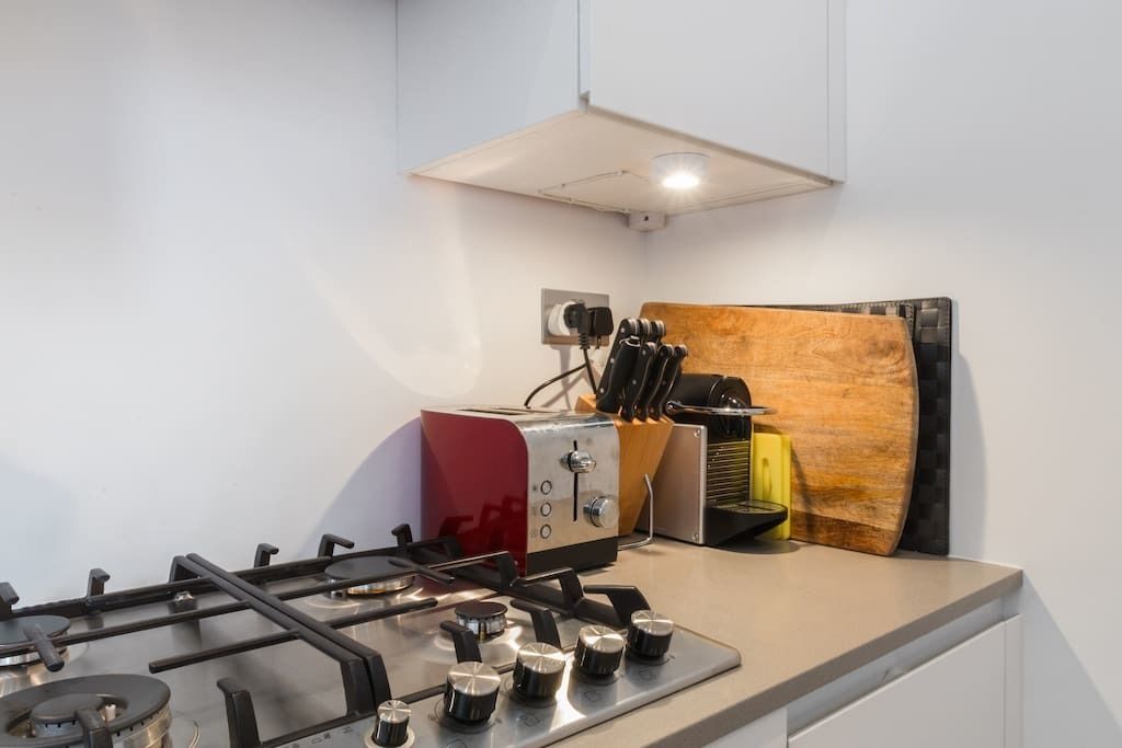 Une cuisine moderne équipée d’une cuisinière à gaz, d’un grille-pain rouge et d’un bloc à couteaux.