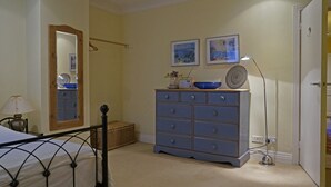 Ein Schlafzimmer mit Bett, Schminktisch, Spiegel und Wandbildern.