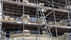 Ein mehrstöckiges Gebäude mit einer Treppe zum Eingang und einem Schild, das vor elektrischen Gefahren warnt.