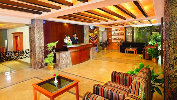 A hotel lobby with a reception desk, seating area, and decorative plants. - The Classik Fort (Kanayannur)