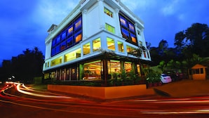 A multi-story hotel with a classic architectural design, featuring large windows and a well-lit facade. - The Classik Fort (Kanayannur)