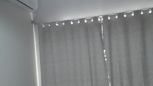 A bedroom with a bed, a nightstand, a lamp, and a window with curtains. - Unai ApartFlat (Unai)