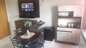 A compact kitchen with a dining area, a TV mounted above the counter, and a refrigerator. - Unai ApartFlat (Unai)