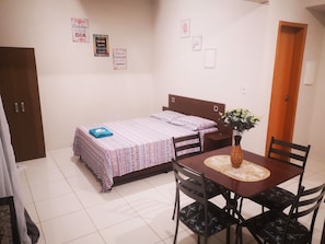 A bedroom with a bed, a table with chairs, and a door.