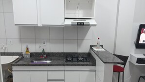 A modern kitchen with white cabinets, a granite countertop, a gas stove, and a small bar stool. - Unai ApartFlat (Unai)