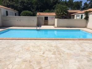 Une piscine rectangulaire, dotée d’une plage carrelée et entourée de murs et d’une porte.