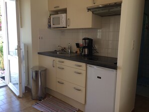A compact kitchen with a microwave, coffee maker, and a small refrigerator.