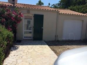 A house with a stone-paved entrance, a green door, and a white garage door.