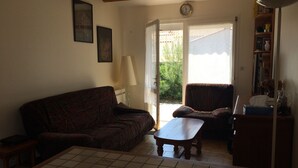 En stue med en sofa, et lille bord og en reol.