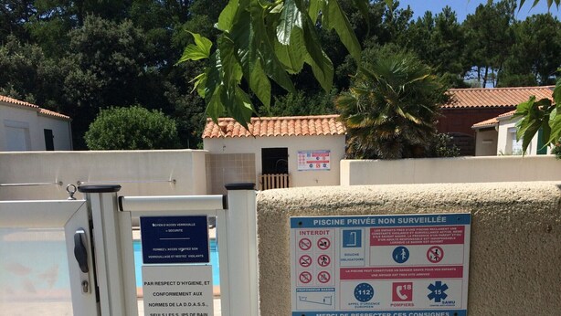 En indhegnet indgang med et skilt, der angiver en privat, uden opsyn holdt swimmingpool.