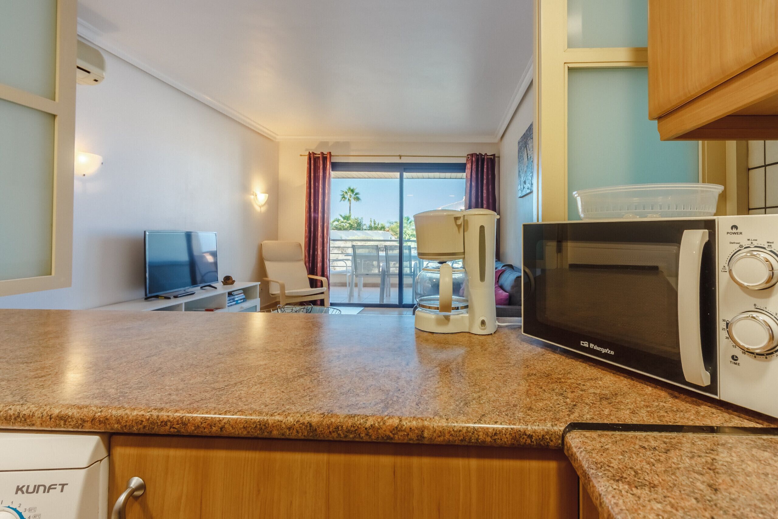 A kitchenette with a microwave, coffee maker, and a TV.