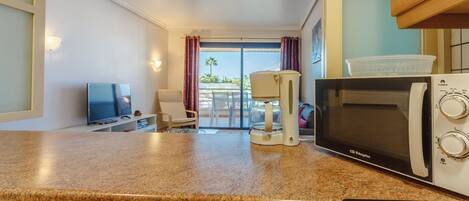 A kitchenette with a microwave, coffee maker, and a TV.