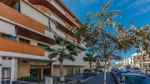 A multi-story hotel with balconies, palm trees, and parked cars. - Balcon de Los Gigantes 2A037 (Acantilados de Los Gigantes)
