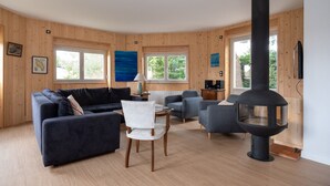 Una sala de estar acogedora con sofá, sillas, una mesa, chimenea y paredes de madera.