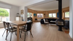 Un interior moderno con comedor, sofás y estufa de leña.