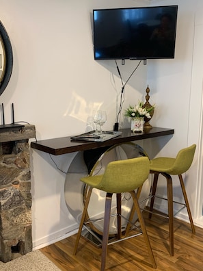 Eine moderne Küche mit integriertem Fernseher, einer Wand aus Naturstein und einer Bar mit Sitzgelegenheiten.