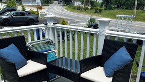 Une terrasse avec deux fauteuils en osier, une petite table et une vue sur la rue.