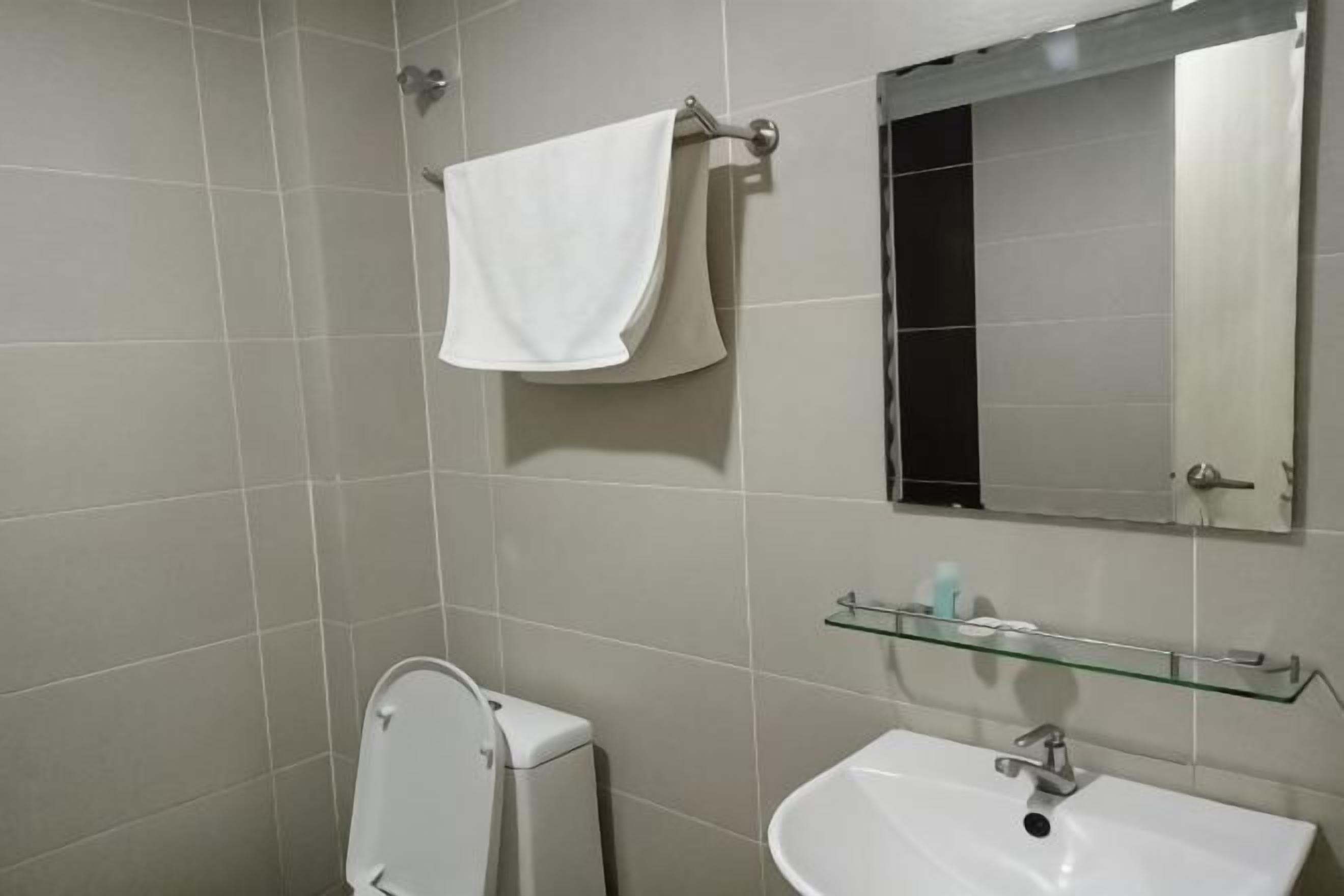 A bathroom with a toilet, sink, mirror, and towel rack.
