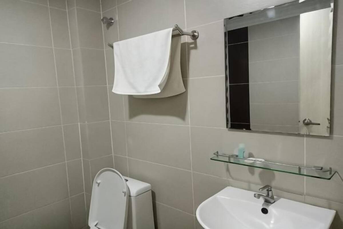 Un baño con inodoro, lavamanos, espejo y toallero.