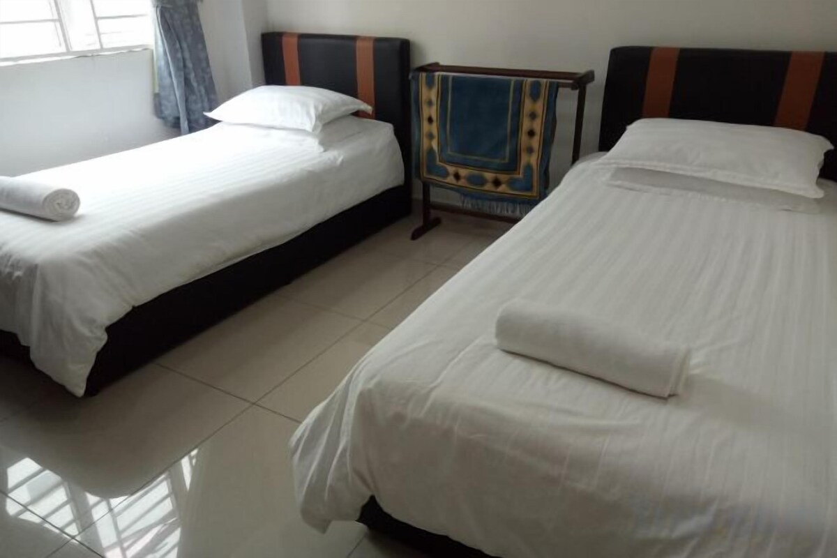A hotel room with two single beds, a nightstand, and a window with curtains.