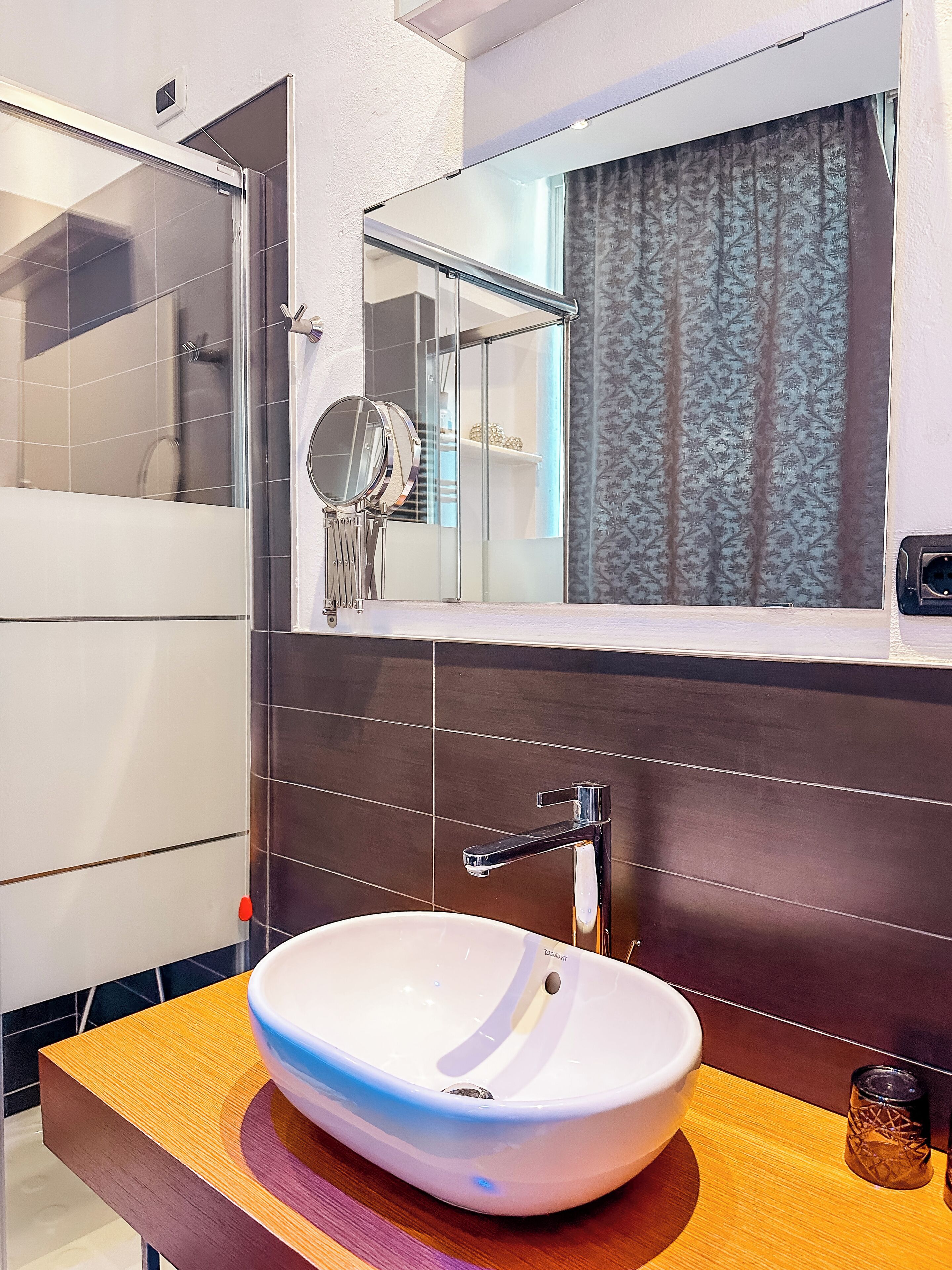 Un bagno moderno con un lavabo a incasso bianco, uno specchio e un box doccia.