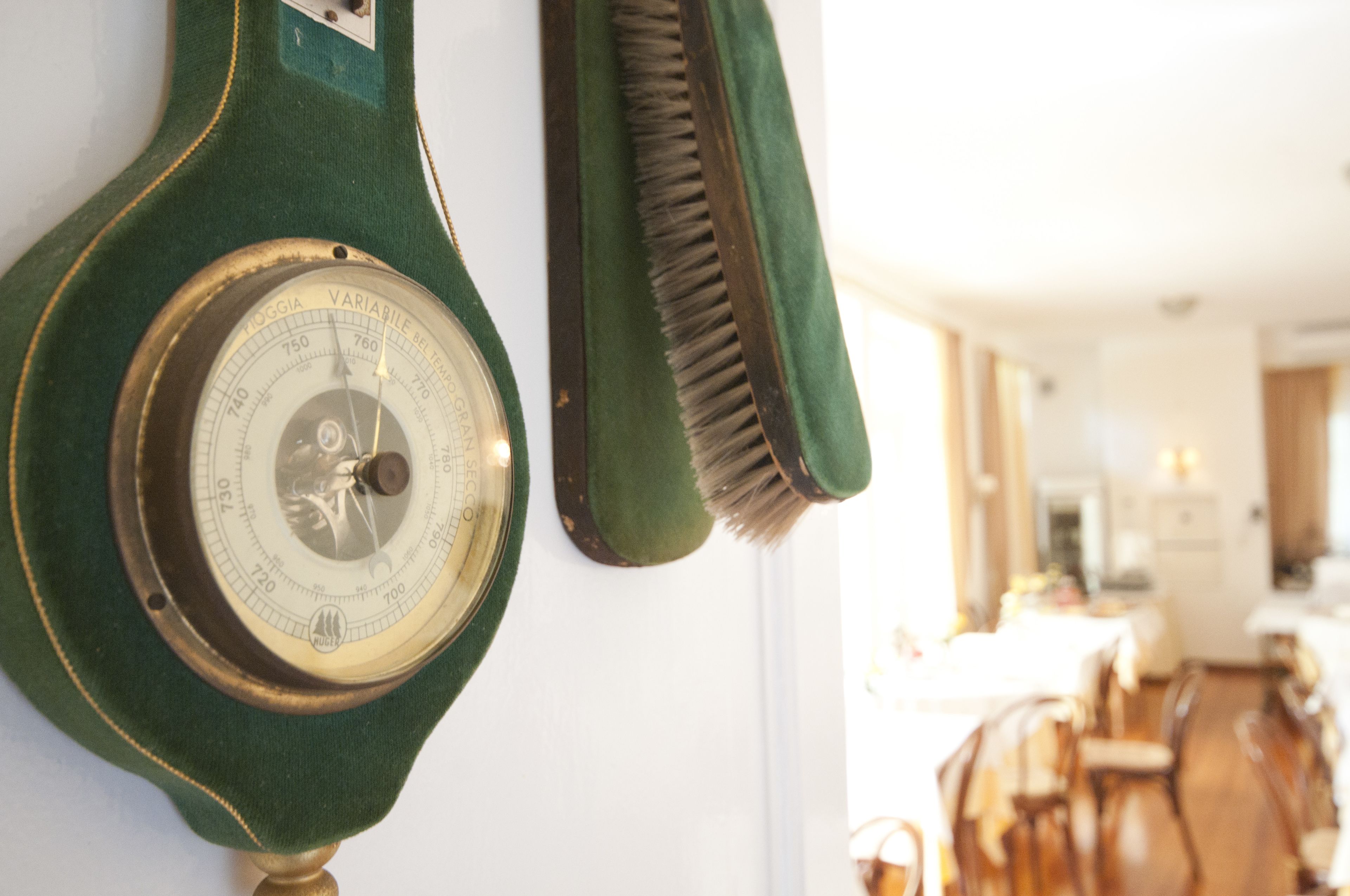 A vintage-style wall clock with a brass face and green fabric cover, mounted on a white wall.