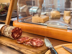 A display of various cured meats and cheeses, including a large sausage and several slices of salami, with a knife and a wooden cutting board. - Hotel Villa Anita (Santa Margherita Ligure)