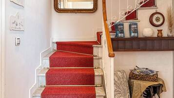 A staircase with red carpeted steps, a wooden handrail, and a mirror above.