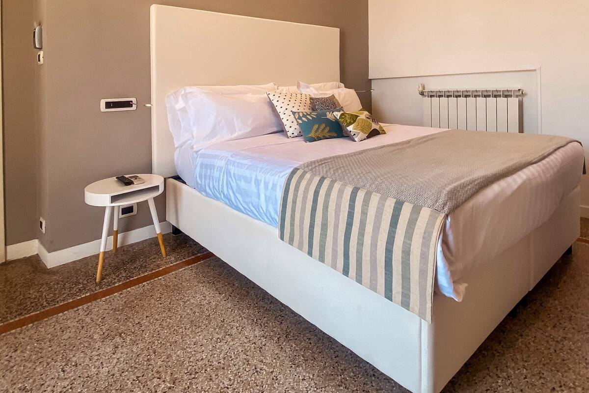 A bedroom with a bed, a bedside table, and a radiator.