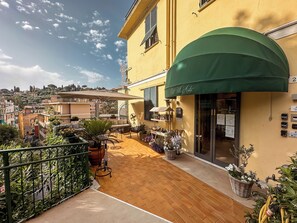 A yellow building with a green awning, outdoor seating, and potted plants. - Hotel Villa Anita (Santa Margherita Ligure)