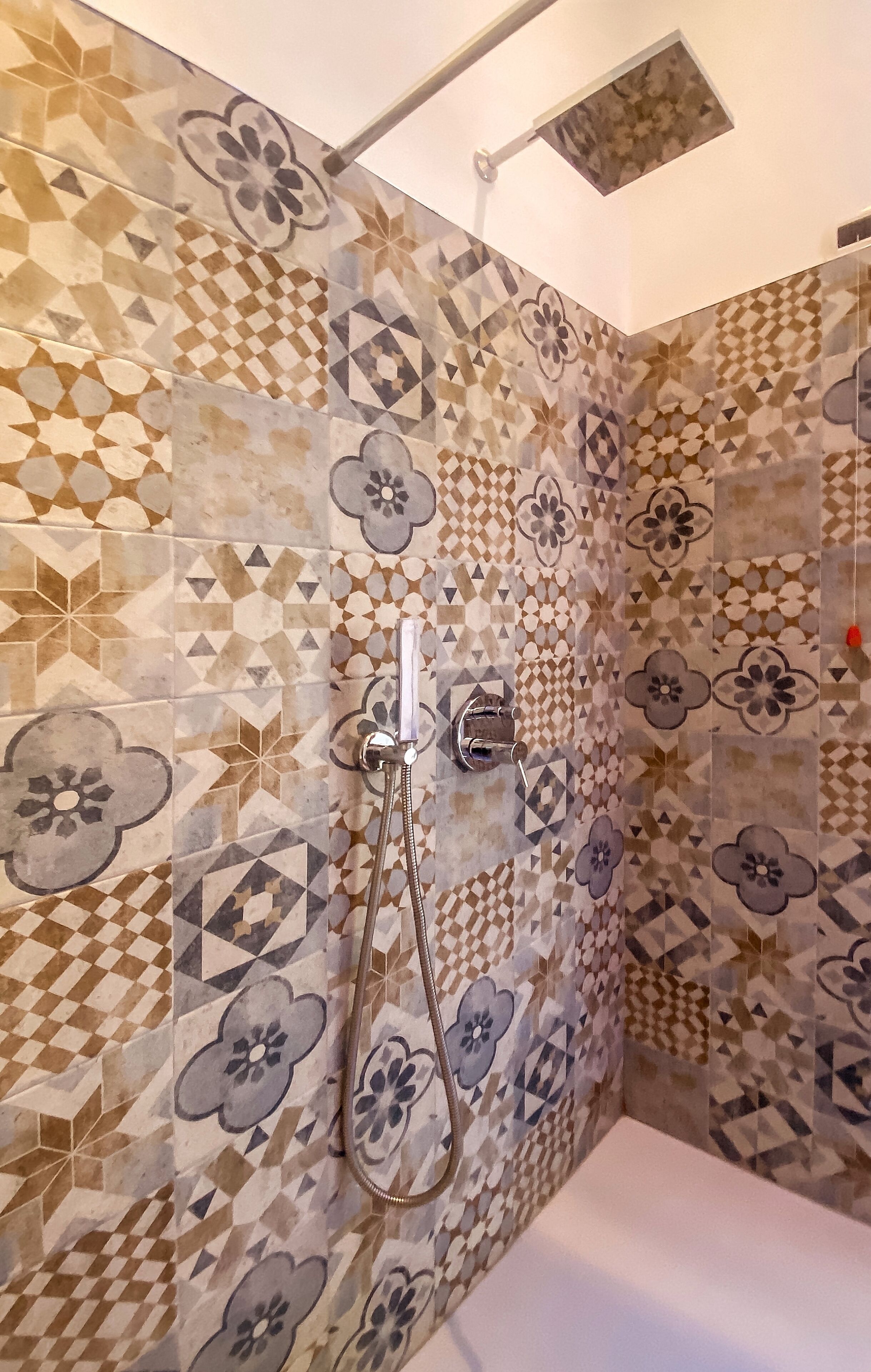 Un baño con baldosas estampadas, ducha e inodoro.