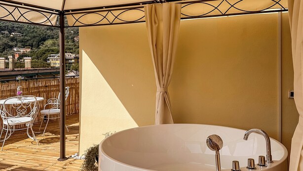 A circular hot tub under a canopy with a view of buildings in the background.