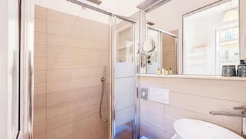 Ein modernes Badezimmer mit einer gläsernen Dusche, einem weißen Waschbecken und einem Spiegel darüber.