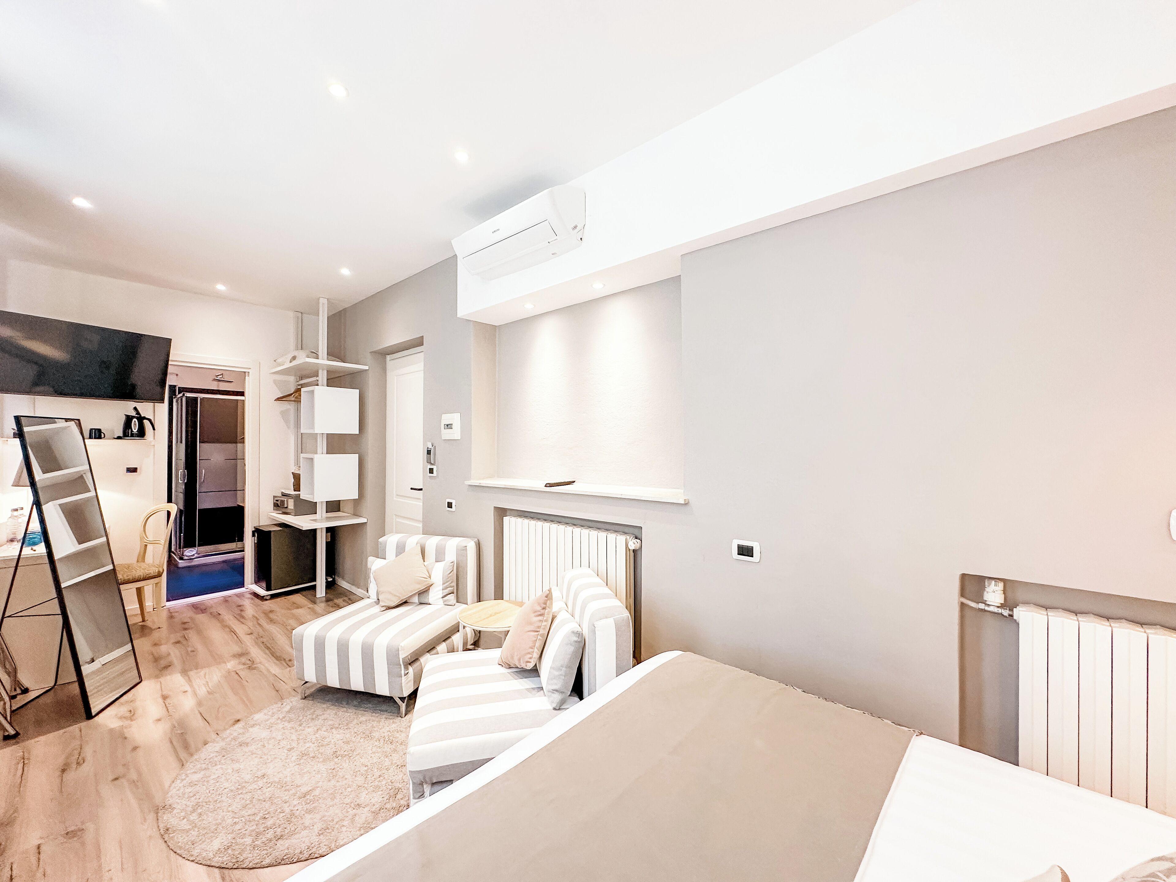 Een moderne slaapkamer met een bed, een sofa, een klein tafeltje en een televisie.
