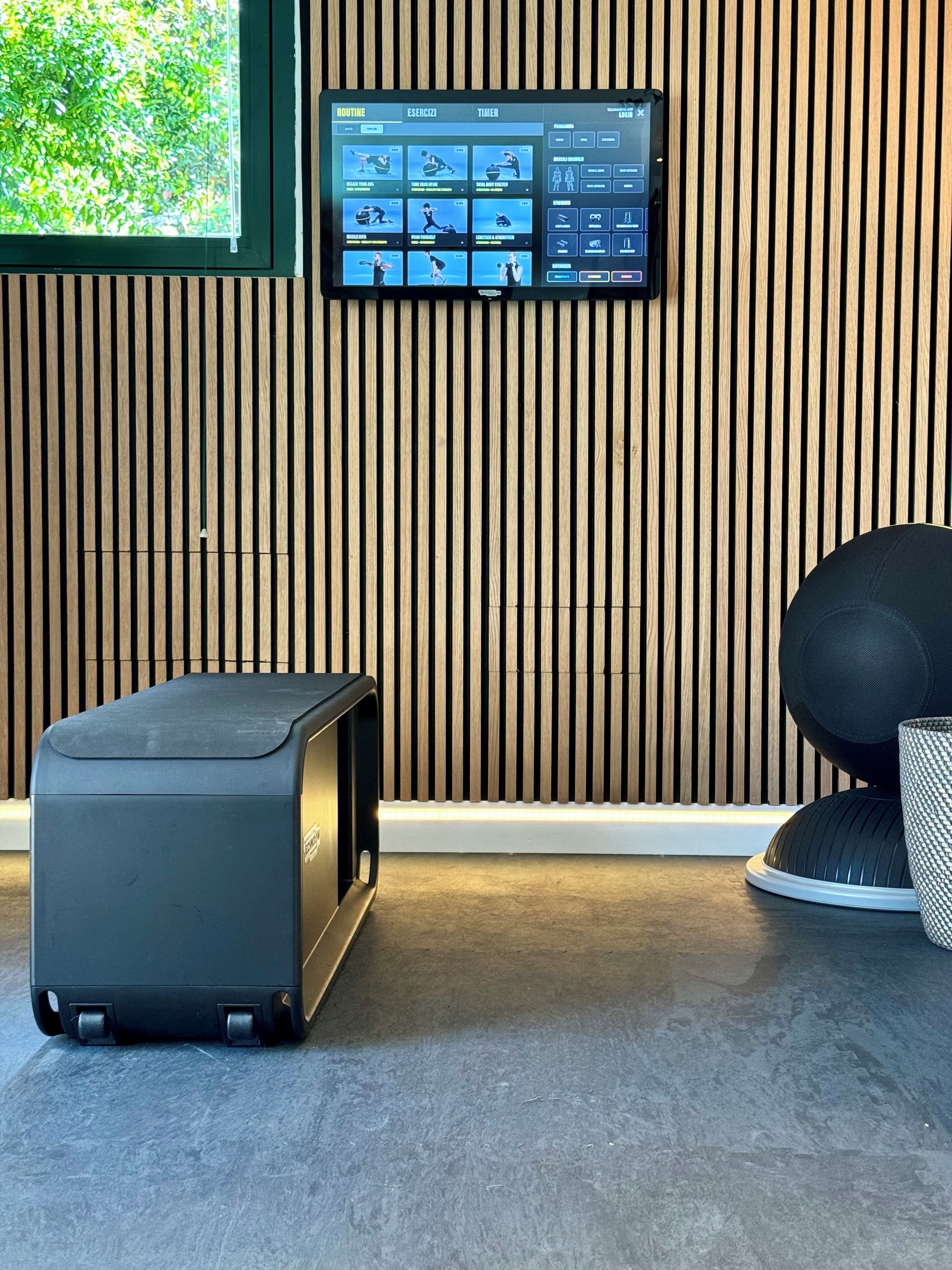 Una camera moderna con parete in listelli di legno, display digitale e forno a microonde compatto.