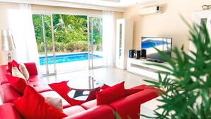A modern living room with a red sofa, a glass coffee table, and a flat-screen TV.