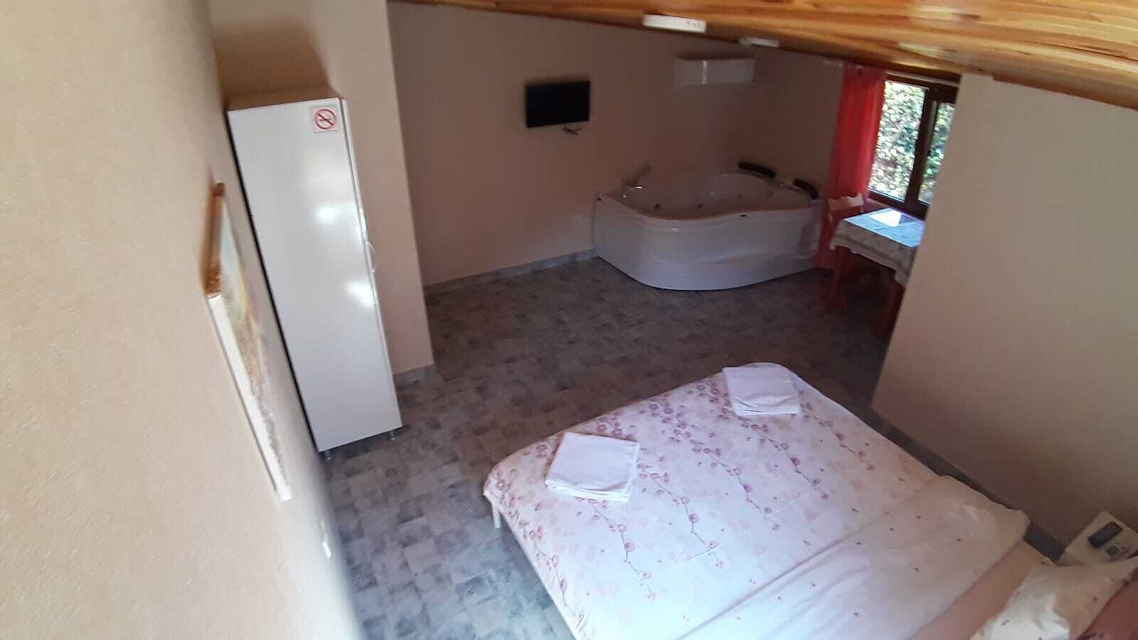 Ein kleiner, kompakter Raum mit einem Bett, einem weißen Kühlschrank und einer Badewanne.