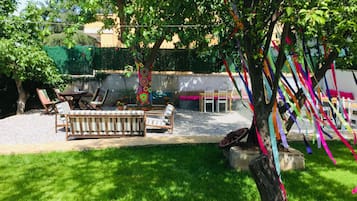 Relax in a serene outdoor space with a bench, chairs, and a small table amidst lush surroundings.