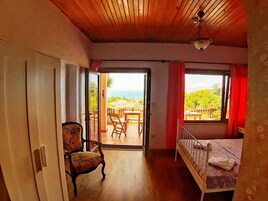 Un dormitorio con techo de madera, una cama, una silla y vistas al exterior a través de una ventana.
