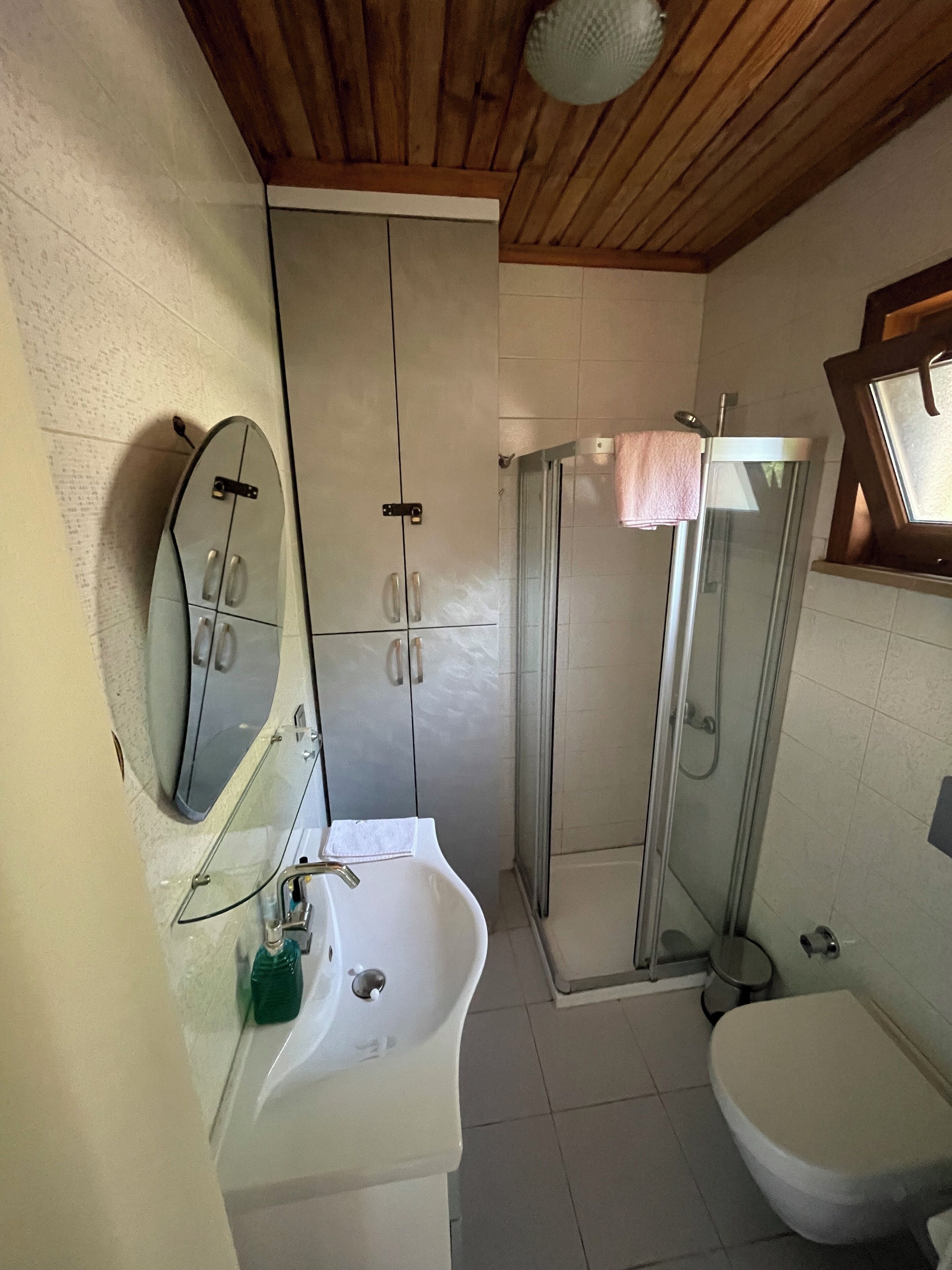 Un baño con lavamanos, inodoro y ducha con mampara de vidrio.