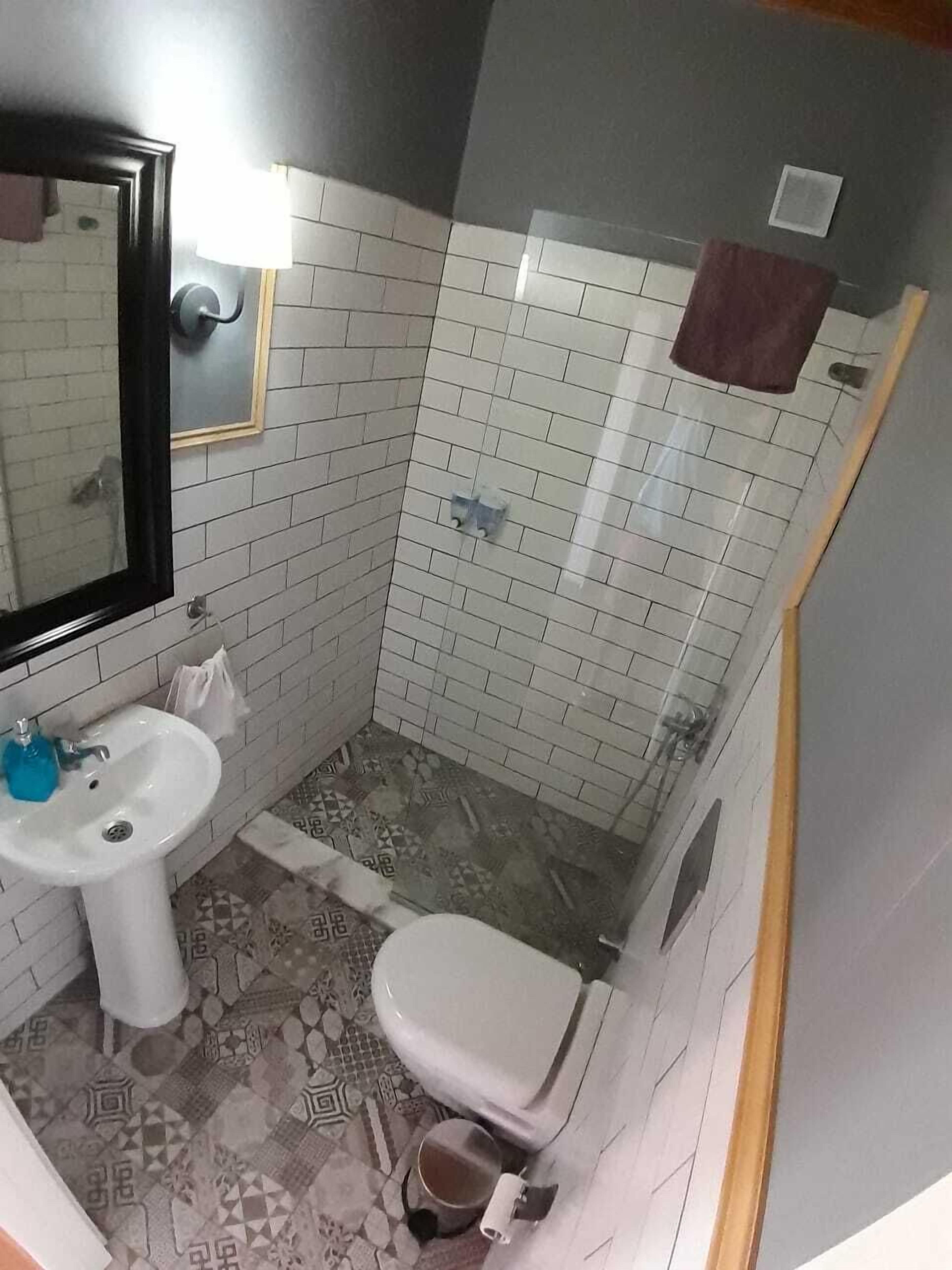 Un baño pequeño con lavamanos, inodoro y ducha blancos.